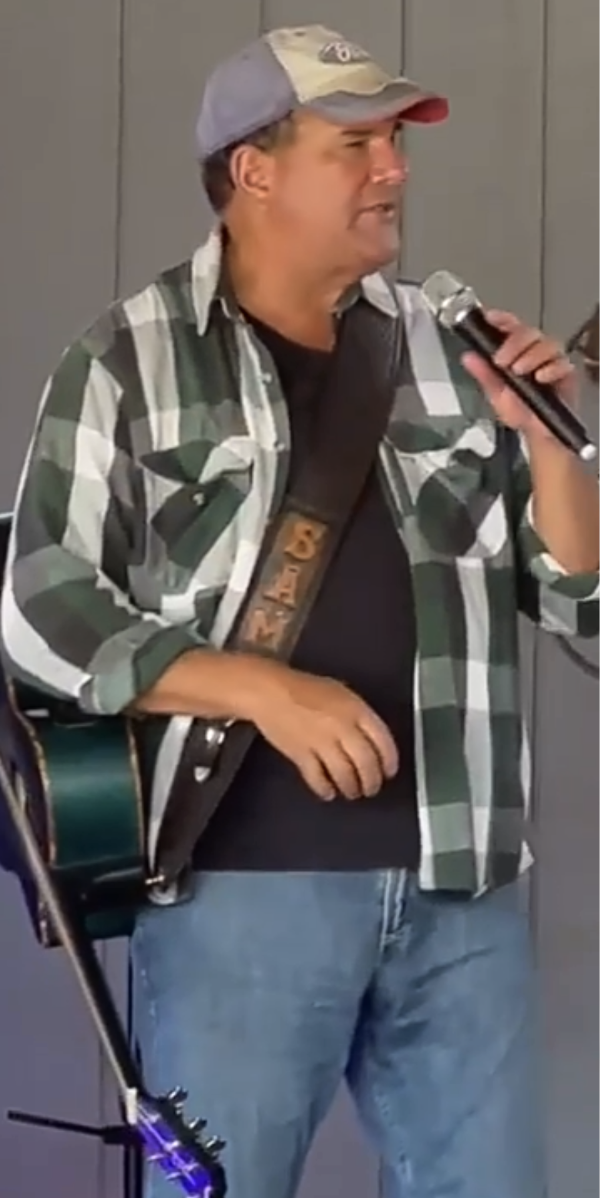 Sam performing live with his guitar and microphone